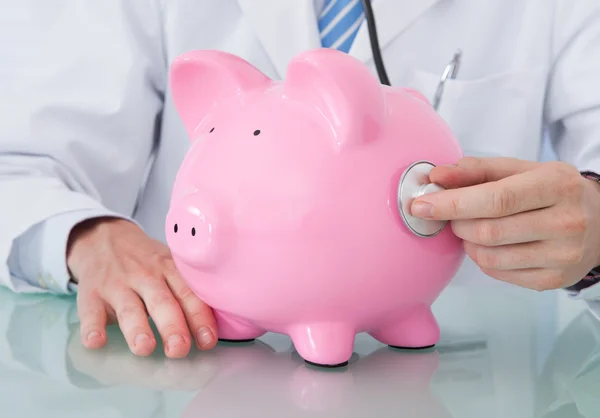 Läkare undersöka piggybank — Stockfoto