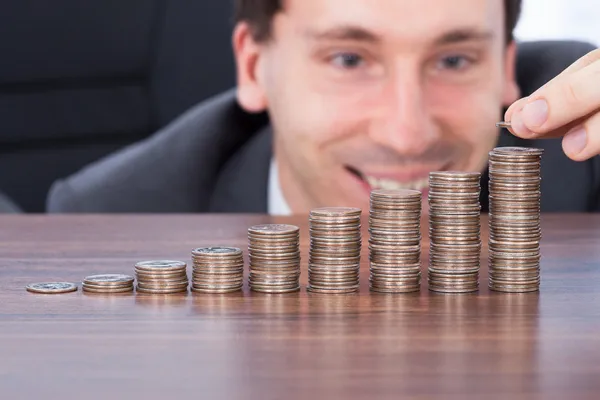 Homem de negócios empilhando moedas na mesa — Fotografia de Stock
