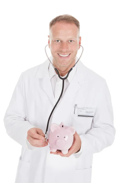 Läkare undersöka piggybank med stetoskop — Stockfoto