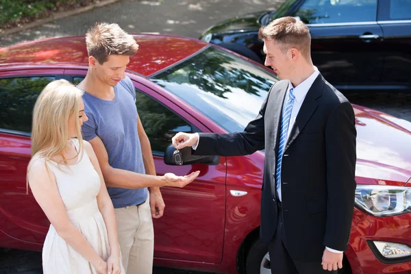 Verkäufer übergibt Schlüssel an Paar — Stockfoto