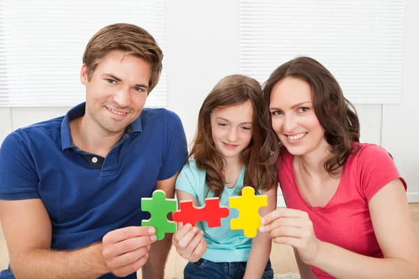 Familia feliz uniéndose a piezas del rompecabezas — Foto de Stock