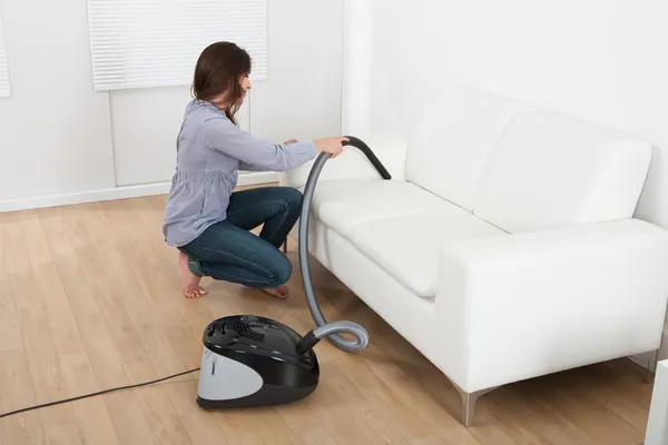 Kvinna vacuuming soffa hemma — Stockfoto