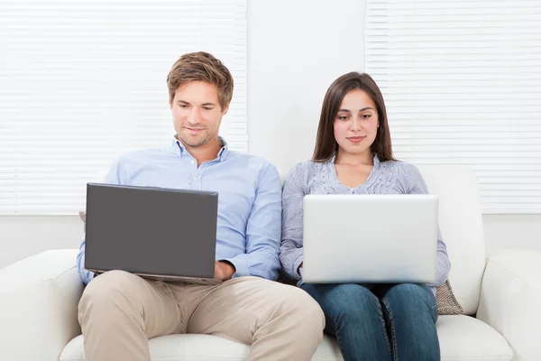 Pareja usando computadoras portátiles — Foto de Stock