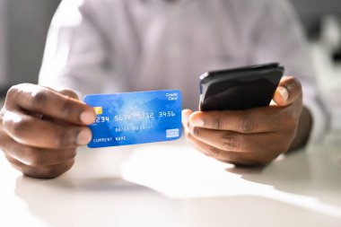 Kredi kartı ve cep telefonu olan kişi çevrimiçi bankacılık yapıyor.