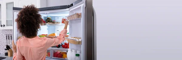 空腹の女性は冷蔵庫から食べる 健康食品を摂取する女性 — ストック写真