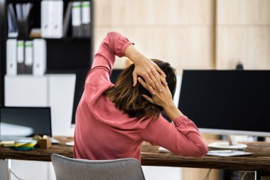 İş kadını ofis masasında esneme egzersizi yapıyor.