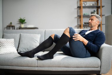 Bacaklarında tıbbi baskı çorapları olan bir adam.