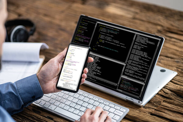 Programmer Coding On Laptop And Smartphone. Mobile Developer