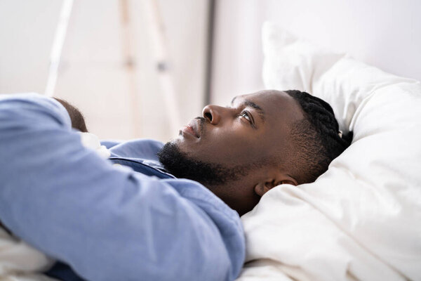 Young Man Suffering From Insomnia Lying In His Bed