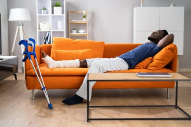 Kırık bacak alçıda iyileşiyor. Koltukta Yaralı Adam