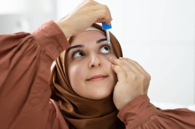 Woman Pouring Eye Drop Medication For Glaucoma And Conjunctivitis clipart