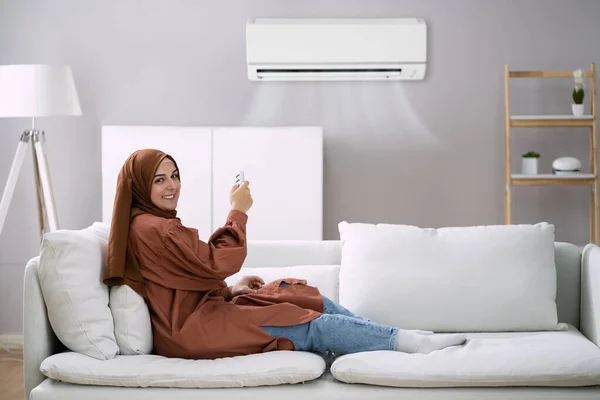 Jeune Femme Sur Canapé Fonctionnant Climatiseur Avec Télécommande — Photo