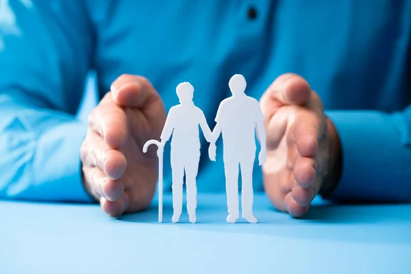 Hand Schützt Senior Couple Cutout Figuren Auf Blauem Hintergrund — Stockfoto