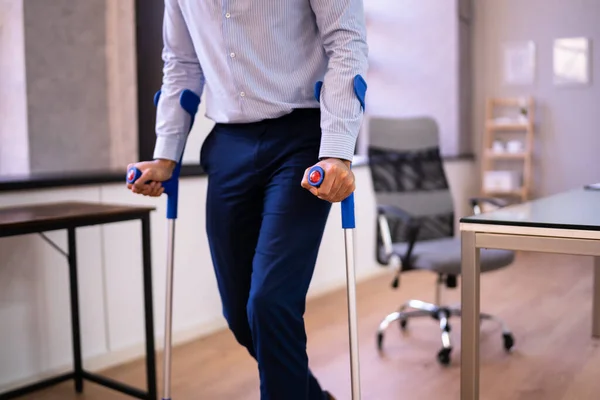 職場やオフィスで松葉杖を持つ労働者 ハンディキャップリハビリテーションの利点 — ストック写真