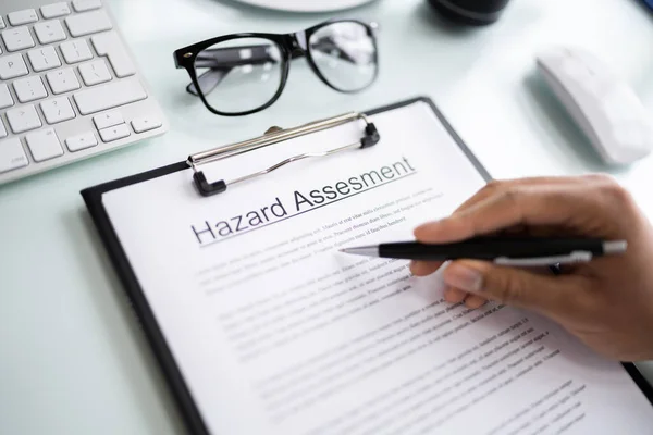 Person Reading Hazard Assessment Document Desk — Stock Photo, Image