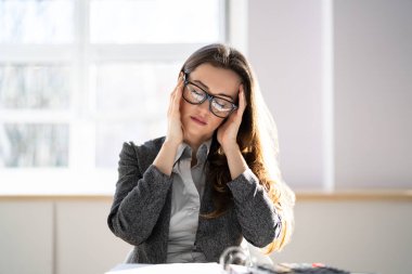 Sıkılmış, mutsuz, üzgün, baş ağrısı ve ağrısı olan genç bir kadın.