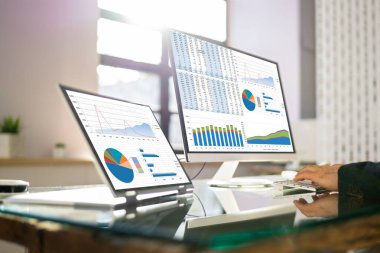 İş adamı ofisteki bilgisayarların grafiklerine bakıyor.