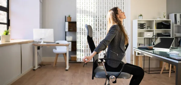 Employee Stretching At Office Desk At Work