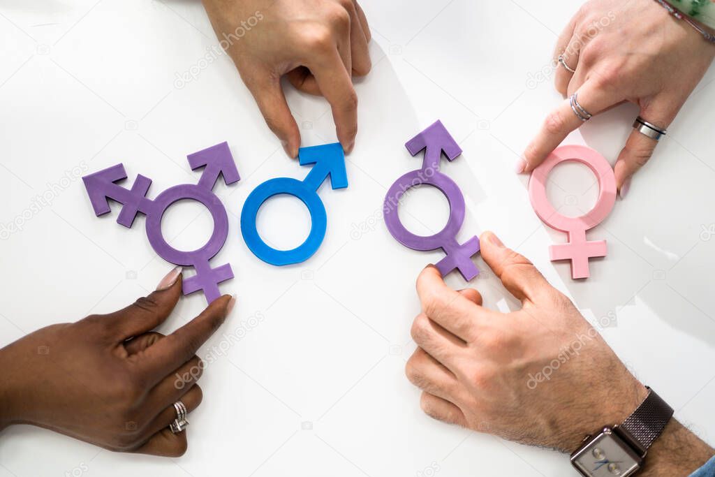 People Holding Different Type Of Gender Sign On White Table
