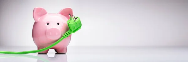 Grön Ström Plug Och Rosa Piggy Bank Reflekterande Skrivbord — Stockfoto