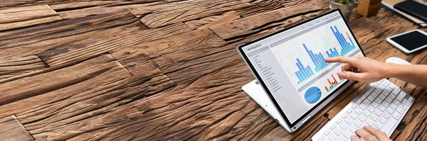 İş kadınının elinin yakın plan fotoğrafı. İş yerindeki bilgisayardaki grafiği analiz ediyor.