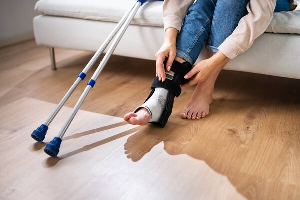 Woman With Leg Injury Using Crutches At Home