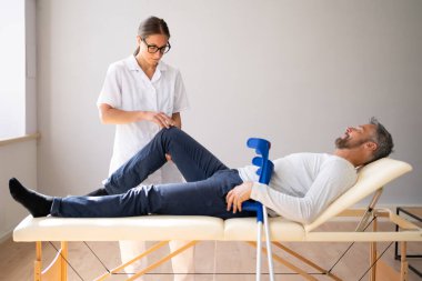 Fizyoterapist erkek hasta dizini kontrol ediyor. Fizyoterapi ve Acı