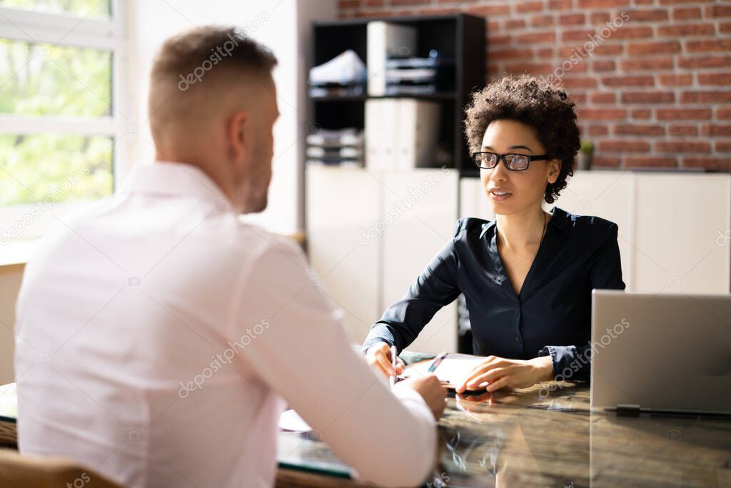 Female Manager Interviewing A Young Male Applicant In Office