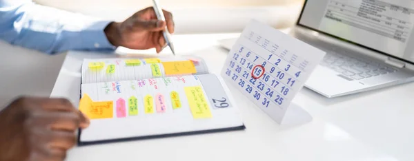ホワイトデスクでカレンダー付きの日記でビジネスマンの手のチェックスケジュール — ストック写真