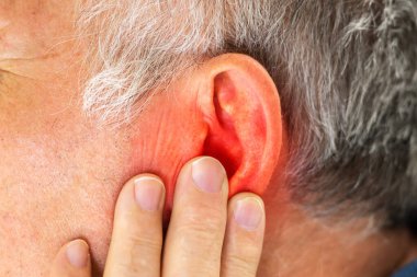 Adam gri arka plan üzerinde el ile kulak kapsayan closeup