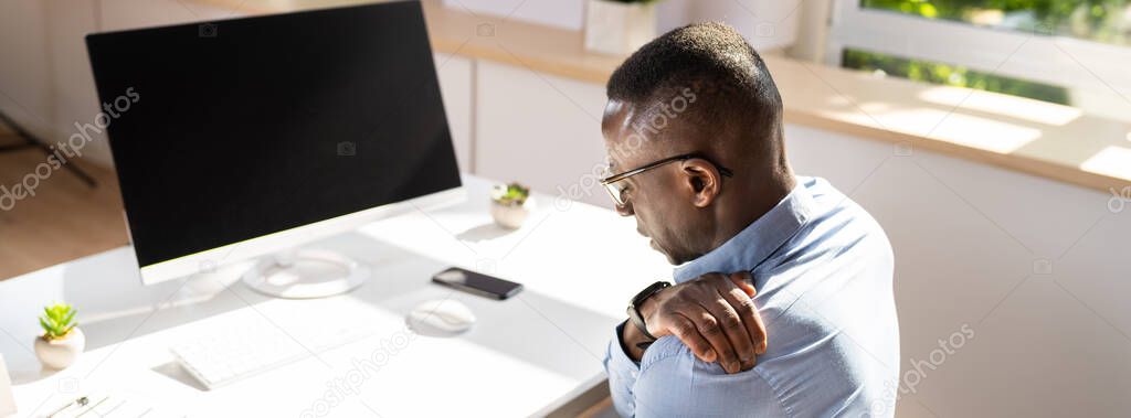 Businessman Suffering From Shoulder Pain While Working In Office