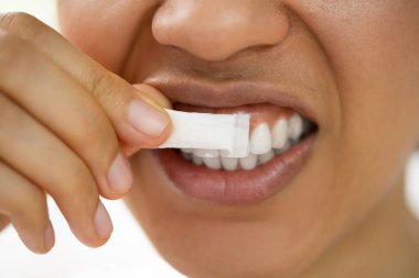Sigarayı bırakmak için nikotin sakızı kullanan bir kadın. Nikotin Değiştirme Terapisi
