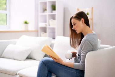 Young Woman At Home With Book And Coffee clipart