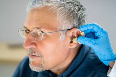 Üst düzey hastanın kulağına işitme cihazı koyarak doktor Close-Up