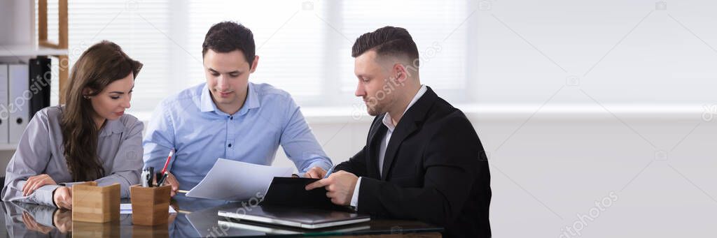 Couple Talking With Advisor During Meeting In Office