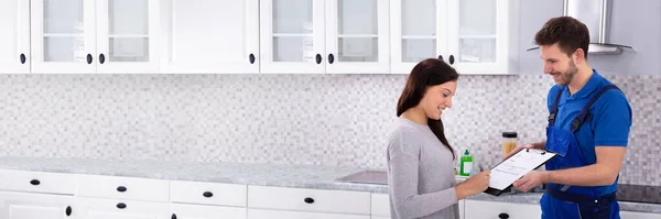 Happy Young Male Plumber Looking Woman Signing Invoice Kitchen — Stock Photo, Image