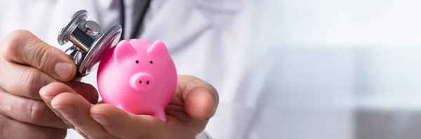 Närbild Läkares Hand Kontroll Rosa Piggybank Med Stetoskop — Stockfoto