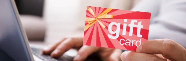 Close Human Hand Holding Gift Card While Using Laptop — Stock Photo, Image