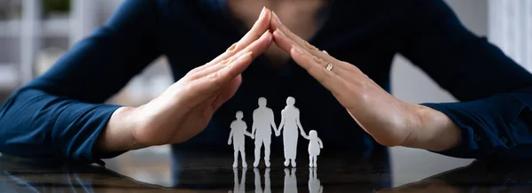 Close Mão Empresário Protegendo Figuras Familiares Mesa Madeira — Fotografia de Stock