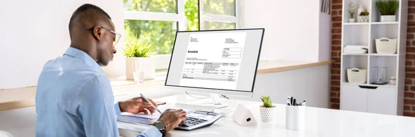 Businessman calculating tax at desk in office