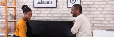 Evde televizyon kaldırma genç Afrikalı çift yan görünüm