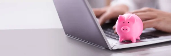 ピンク ピギーバンクとノートパソコンで働くビジネスマンの手 — ストック写真