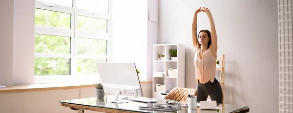 Young Businesswoman Stretching At Workplace In Office