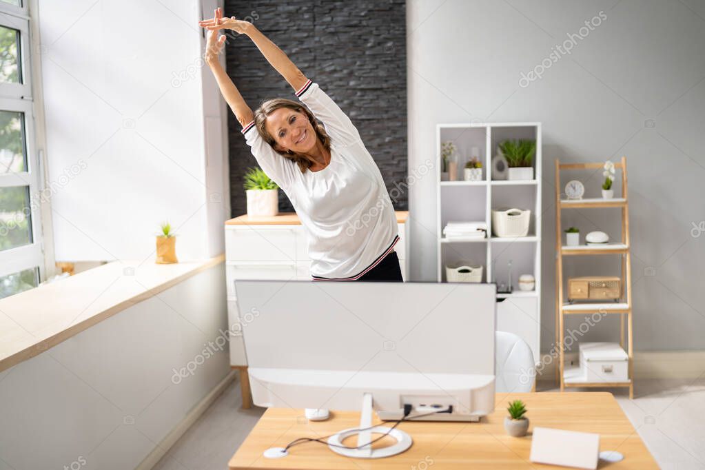 Young Businesswoman Stretching Her Arms At Desk