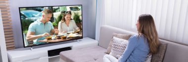 Evde televizyon izlerken koltukta oturan kadın olgun
