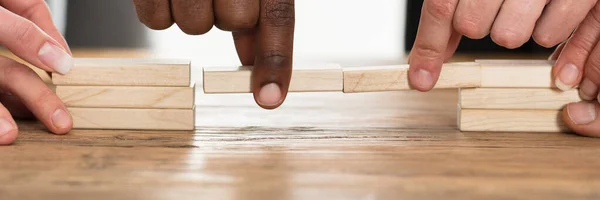 Businesspeople Hand Holding Wooden Building Blocks Form Bridge Gap Table — Stockfoto