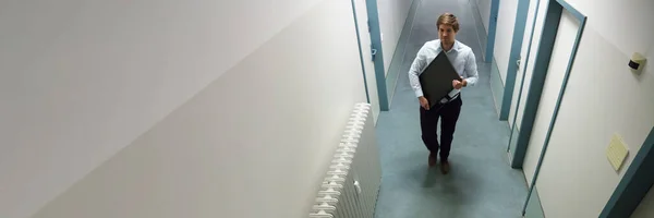 男子偷电脑监视器行走在建筑走廊上 — 图库照片