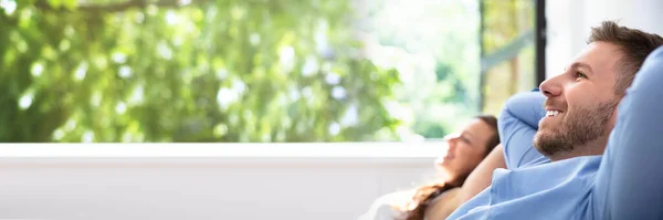 Χαμογελαστά Νεαρό Ζευγάρι Χαλαρωτικό Κάθεται Στον Καναπέ Στο Σπίτι — Φωτογραφία Αρχείου
