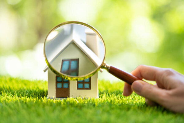 Инспектор по недвижимости проверяет недвижимость с помощью увеличительного стекла