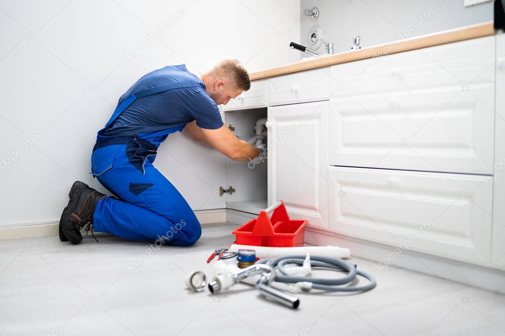 Male Plumber In Overall Fixing Sink Pipe